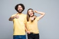 Joyful happy young family couple looking and pointing thumbs up at camera, isolated on grey white studio background Royalty Free Stock Photo