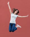 Joyful happy young woman jumping against red wall, beautiful girl enjoy life