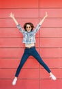 Joyful happy young woman jumping against red wall. Excited beautiful girl portrait Royalty Free Stock Photo