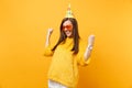 Joyful happy young woman in orange heart glasses, birthday party hat clenching fists like winner enjoying holiday