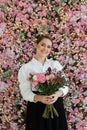Joyful healthy woman smiling and holding colorful pink color flower bouquet on floral spring or summer background, studio fashion Royalty Free Stock Photo