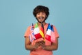 Happy Hindu Guy With Diverse Flags in Blue Studio Background Promoting Education Abroad Royalty Free Stock Photo
