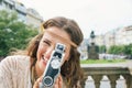 Joyful hippy-looking woman tourist using retro camera in Prague