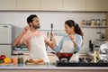 Joyful Indian couples at kitchen dancing together while cooking together during weekend holidays - concept of