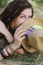 Joyful indie style woman with dreadlocks hairstyle, have a fun closing her face with a hat