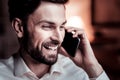 Joyful interested man holding his cellphone near head and laughing. Royalty Free Stock Photo