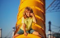 Joyful kid boy having fun on playground outdoors. Thumbs up. Happy blond kid boy having fun and sliding on outdoor Royalty Free Stock Photo