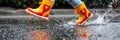 Joyful kid in rain boots gleefully leaping into a puddle, offering a perfect spot for adding text. Royalty Free Stock Photo