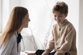 Joyful kid visiting pediatrician, sitting on medical couch in office Royalty Free Stock Photo