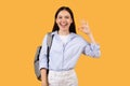 Joyful lady giving okay sign, wearing backpack