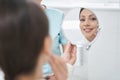 Cheerful woman looking in the mirror in cosmetology clinic Royalty Free Stock Photo