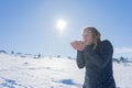 Joyful lady in wintertime blowing snow from her hand with vitality on mount Royalty Free Stock Photo