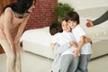 Joyful latin children, teenage girl and two little twin boys hugging each other while having fun indoors. Mom and dad Royalty Free Stock Photo