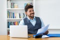 Joyful laughing hispanic businessman with computer and paperwork