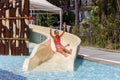Joyful laughing teen girl goes down by water slide in the hotel aquapark Royalty Free Stock Photo
