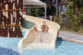 Joyful laughing teen girl goes down by water slide in the hotel aquapark Royalty Free Stock Photo