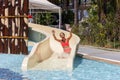 Joyful laughing teen girl goes down by water slide in the hotel aquapark Royalty Free Stock Photo