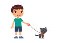 A joyful little boy is holding a cute black kitten on a harness. Royalty Free Stock Photo