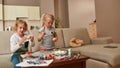 Joyful little children, brother and sister painting colorful Easter eggs, sitting on a couch while spending time Royalty Free Stock Photo
