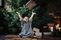 Joyful little girl with blonde curly hair wearing a warm sweater throws up a gift box while sitting on a floor next to Royalty Free Stock Photo