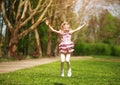 Joyful little girl child jumping from happiness in spring green park Royalty Free Stock Photo