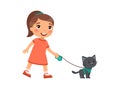 A joyful little girl is holding a cute black kitten on a harness. Royalty Free Stock Photo