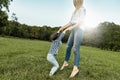 Joyful little girl playing with her mother on green grass. Loving beautiful woman and her daughter spending time together and Royalty Free Stock Photo