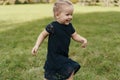 Joyful little girl running on green grass