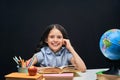 Joyful little girl sitting at the table with pencils and books textbooks. Happy child pupil doing homework at the table Royalty Free Stock Photo