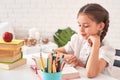 Joyful little girl sitting at the table with pencils and textbooks. Happy child pupil doing homework at the table.beautiful Royalty Free Stock Photo