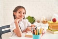 Joyful little girl sitting at the table with pencils and textbooks. Happy child pupil doing homework at the table.beautiful Royalty Free Stock Photo