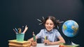 Joyful little girl sitting at the table with pencils and textbooks. Happy child pupil doing homework at the table Royalty Free Stock Photo