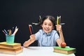 Joyful little girl sitting at the table with pencils and textbooks. Happy child pupil doing homework at the table Royalty Free Stock Photo