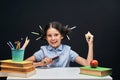 Joyful little girl sitting at the table with pencils and textbooks. Happy child pupil doing homework at the table Royalty Free Stock Photo