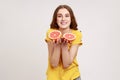 Joyful lively bright teenager girl wearing casual style attire showing half slice grapefruit to Royalty Free Stock Photo