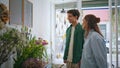 Joyful lovers shop flowers in florist store. Multiracial couple enjoy bouquet. Royalty Free Stock Photo