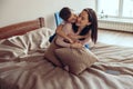 Joyful loving caucasian mother and small playful son hugging and playing on bed at home. Royalty Free Stock Photo