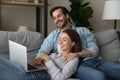 Joyful loving young family couple watching funny movie on computer.