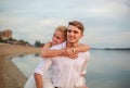 Joyful loving young newlywed couple in each other`s arms on city beach