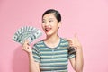 Joyful lucky girl hold lot of money, pointing at dollar bills in hand and smiling excitedly, enjoying lottery win