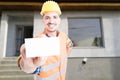 Joyful male builder showing blank visit card Royalty Free Stock Photo
