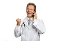 Joyful male doctor talking on phone.