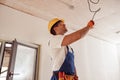 Joyful male electrician repairing electric cable on ceiling Royalty Free Stock Photo