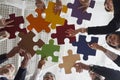 Joyful male and female office workers put together colored pieces of puzzle at meeting in office. Royalty Free Stock Photo