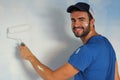 Joyful male painting a wall with a roller and smiling