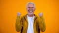 Joyful male pensioner showing success gesture and smiling on camera satisfaction