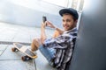 Joyful male skater entertaining with smartphone