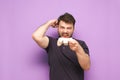 Joyful man with beard holds gamepad and rejoices in victory on pink background. Gamer with joystick in hands joyous victory.
