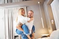 Joyful man carrying his smiling pleased wife to the bed