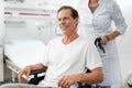 Joyful man sitting in wheelchair while nurse standing behind him Royalty Free Stock Photo